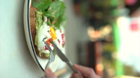 Breakfast plate with egg and arugula - Woman eats the egg by bursting it Video stock 194372127