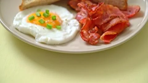 Breakfast plate with fried egg bacon and toast on beige plate Stock Photos