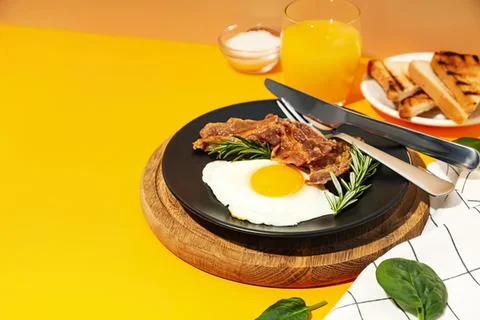Breakfast plate with fried egg bacon toast and herbs Foto stock