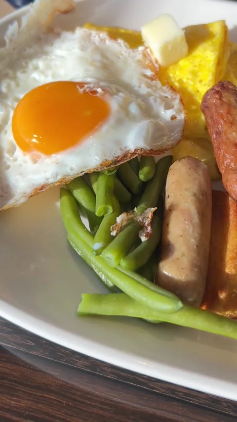 Breakfast plate with fried egg, sausages, potatoes, vegetables, and salad  Stock-Footage 333762734