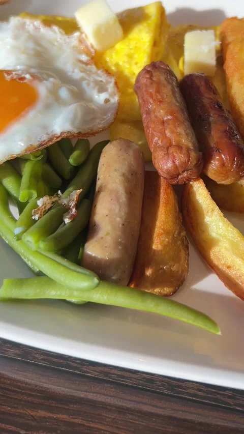 Breakfast plate with fried egg, sausages, potatoes, vegetables, and salad  Stock Footage 333762735
