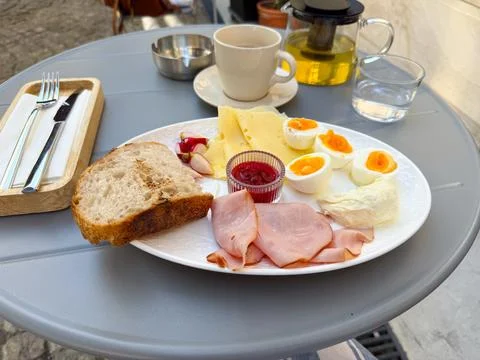 A breakfast plate with ham, cheese, eggs, bread, and jam served with tea. Nut Stock Photos