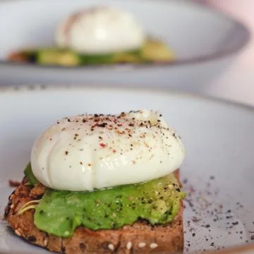 Breakfast on a plate - poached eggs on bread with avocado, close-up Stock Photos