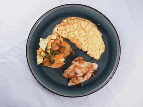 Breakfast plate with scrambled eggs, meat and vegetable salad Stock Photos