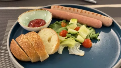 Breakfast plate with sliced bread, sausage, salad, and condiment on a blue .. Stock Footage 331090273