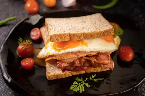 Breakfast sandwich made with bread, fried egg, ham, and lettuce. Foto stock