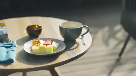 Breakfast scene with coffee cup and plate of food on a wooden table outdoors Video stock 328043173
