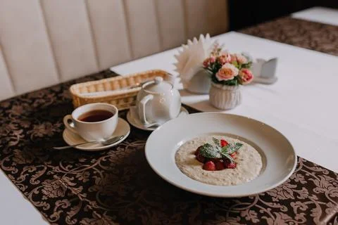 Breakfast scene with a steaming cup of tea placed beside a bowl of oatmeal Stock Photos