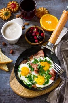 Breakfast scrambled eggs with bacon, coffee, berries, cookies, nuts and juice. Stock Photos