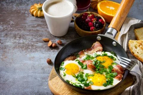 Breakfast scrambled eggs with bacon, coffee, berries, cookies, nuts and juice. Stock Photos
