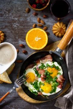 Breakfast scrambled eggs with bacon, coffee, berries, cookies, nuts and juice. Stock Photos