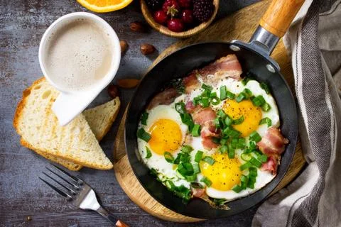 Breakfast scrambled eggs with bacon, coffee, berries, cookies, nuts and juice. Stock Photos