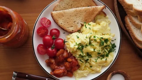 Breakfast scrambled eggs, bread toast, tomatoes and beans Stock Footage 142744240