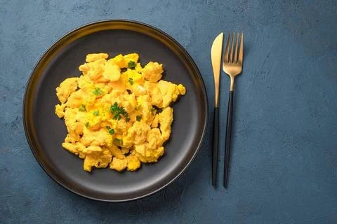 Breakfast with scrambled eggs on a dark background. Stock Photos