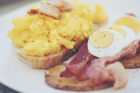 Breakfast with scrambled eggs, fried potatoes bacon and shrimp Stock Photos