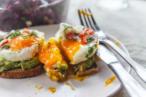 Breakfast served of two toasts with avocado, fried eggs with vegetables and h Stock Photos