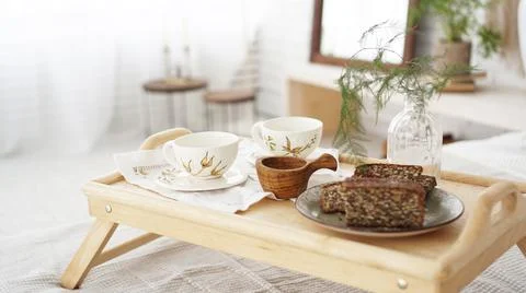Breakfast set close up in the room. Cups on a tray with vase on the bed Stock Photos