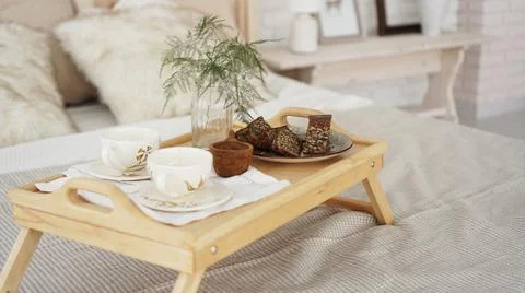 Breakfast set close up in the room. Cups on a tray with vase on the bed Stock Photos