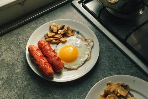 Breakfast set of fried egg and sausages with mushroom in the kitchen. Stock-Fotos