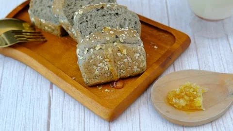 Breakfast set A man's hand is pouring honey onto bread with milk. Stock Footage 257163593