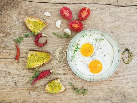 Breakfast set with roasted eggs, bread toasts with pesto sauce, cherry-tomato Stock Photos