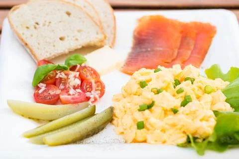 Breakfast set, scrambled eggs with chives, fish, cucumber, tomato and bread Stock Photos