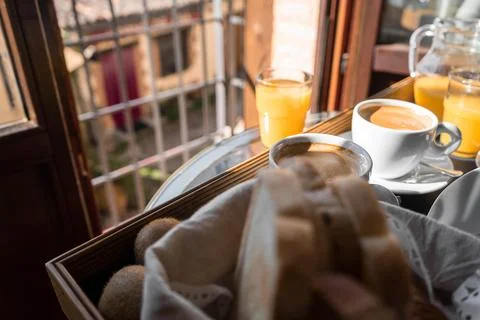 A breakfast setting on a balcony with a basket of bread, a cup of coffee, and Stock Photos