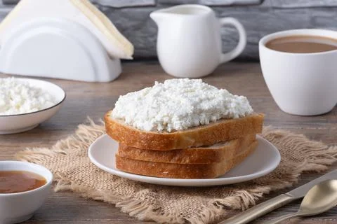 Breakfast setup with bread, cottage cheese, coffee, and jam on a wooden tab.. Foto stock