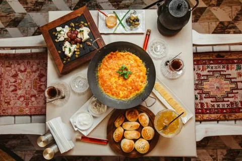 Breakfast setup with egg and tomato dish, cheese plate, bread buns Stock Photos