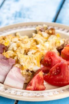 Breakfast with sliced raw bacon and fried eggs with tomato salad Stock Photos