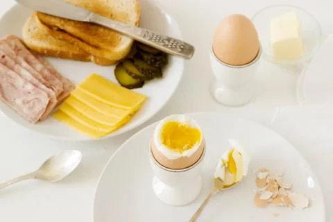 Breakfast with soft-boiled egg, bread toast, ham, cheese and canned cucumbers Stock Photos