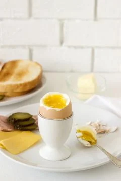 Breakfast with soft-boiled egg, bread toast, ham, cheese and canned cucumbers Stock Photos
