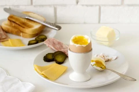 Breakfast with soft-boiled egg, bread toast, ham, cheese and canned cucumbers Stock-Fotos