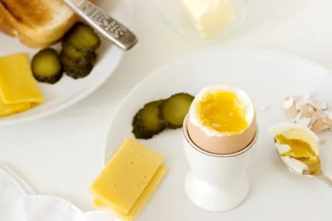 Breakfast with soft-boiled egg, bread toast, ham, cheese and canned cucumbers Stock Photos