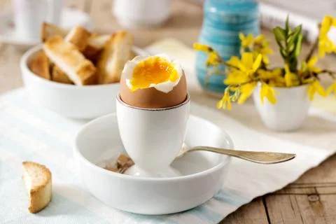 Breakfast from soft-boiled egg, bread toast, coffee with cream and fresh Stock Photos