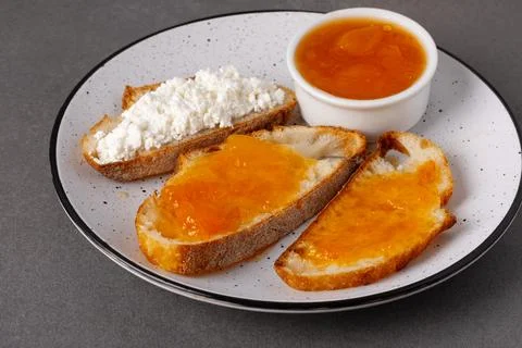Breakfast spread with bread, cottage cheese, and fruit jam served on a plate Фото