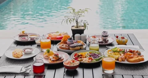Breakfast spread resting on table beside luxury swimming pool Видео 335186178