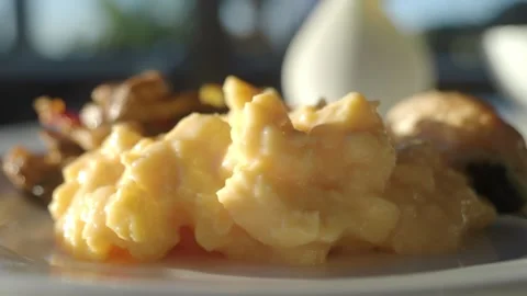 Breakfast spread with scrambled eggs, mushrooms, and pastry on white plate .. Stock Footage 332907543