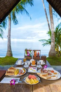 Breakfast table on the beach with palm trees in Thailand Stock Photos