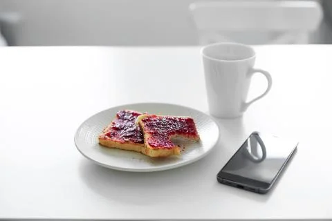 Breakfast is on the table. A cup of coffee and toast with cherry jam next to  Stock Photos