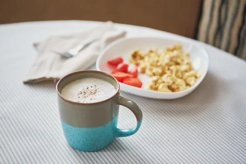 Breakfast table. Cup of coffee and plate with scrambled eggs and vegetables o Fotos Stock