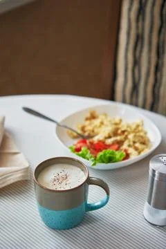 Breakfast table. Cup of coffee and plate with scrambled eggs and vegetables.. Stock Photos