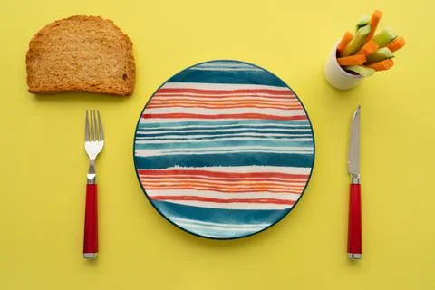 Breakfast table empty colorful plate, toasted bread and sliced carrot and cuc Stock-Fotos