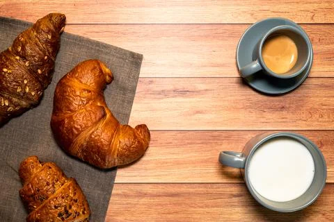 Breakfast table with espresso, milk and croissants of various flavors. Stock Photos