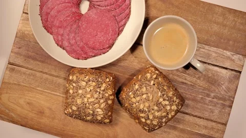 Breakfast table with fresh bread rolls and sausage - top down view 스톡 동영상 151058634