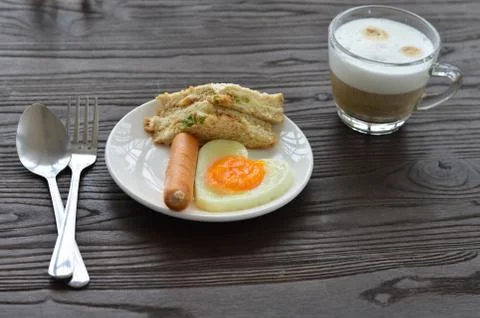 Breakfast on the table has fried eggs, sausages, sandwiches and coffee. Stock Photos