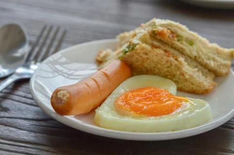 Breakfast on the table has fried eggs, sausages, sandwiches. Stock Photos