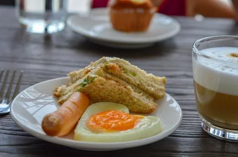 Breakfast on the table has fried eggs, sausages, sandwiches and coffee. Stock Photos