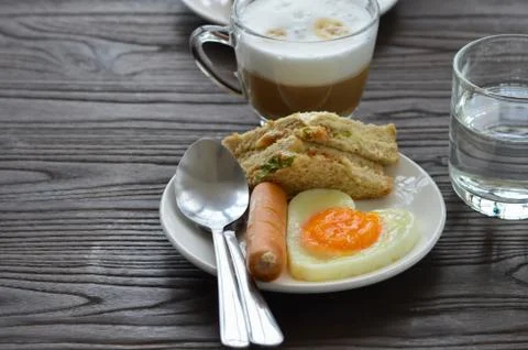 Breakfast on the table has fried eggs, sausages, sandwiches and coffee. Stock Photos