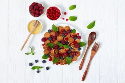 Breakfast table mini pancakes berries mint leaves and honey from above Stock Photos